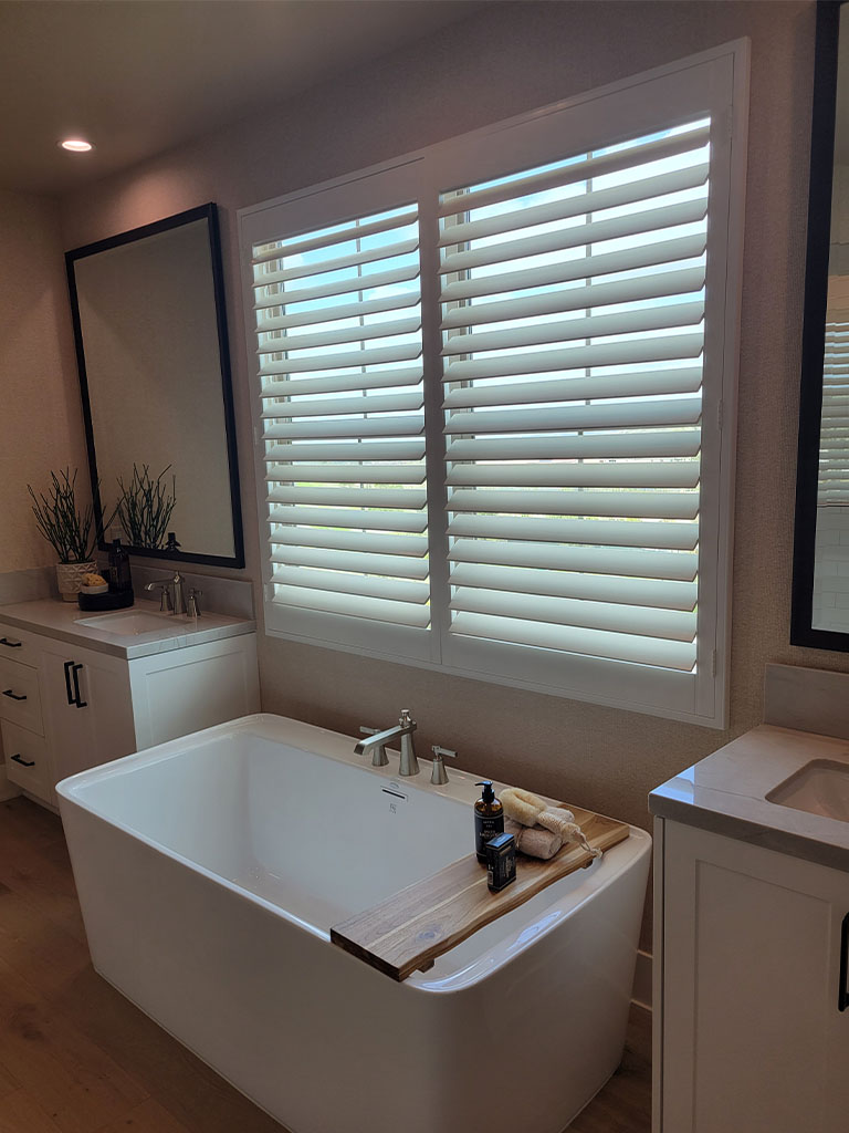 White plantation shutters in a sunny Orange County home interior, showcasing energy efficiency and privacy